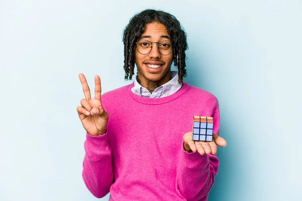 Mladý Afroameričan Drží Kostku Rubiks Izolované Modrém Pozadí Ukazující Číslo — Stock fotografie
