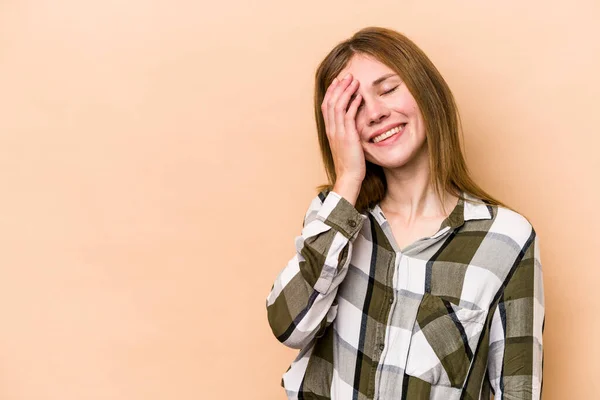 Young English woman isolated on beige background laughing happy, carefree, natural emotion.
