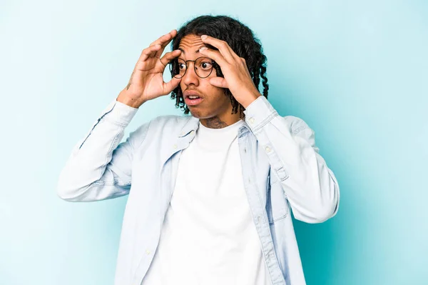 Молодой Африканский Американец Изолированный Синем Фоне Держит Глаза Открытыми Найти — стоковое фото