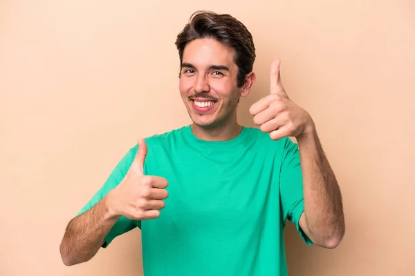 Jovem Caucasiano Isolado Fundo Bege Levantando Dois Polegares Sorrindo Confiante — Fotografia de Stock