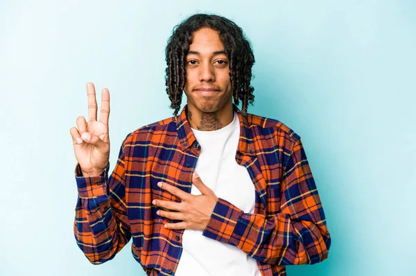 Genç Afrikalı Amerikalı adam mavi arka planda izole edilmiş bir şekilde yemin ediyor, elini göğsüne koyuyor..