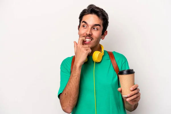 Young caucasian student man drinking coffee isolated on white background relaxed thinking about something looking at a copy space.