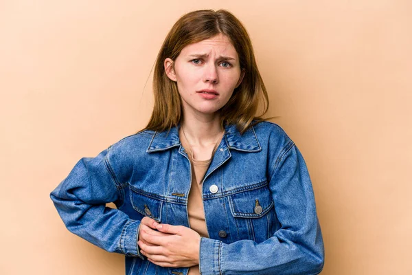 Young English woman isolated on beige background having a liver pain, stomach ache.