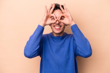 Beyazlı genç bir adam bej arka planda izole edilmiş, gözlerde sorun yok işareti var.