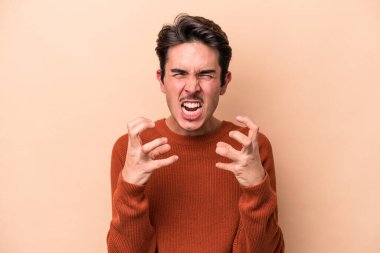 Beyazlı genç adam bej arka planda izole edilmiş gergin elleriyle çığlık atıyor..