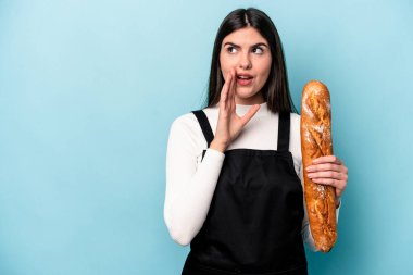 Mavi arka planda izole edilmiş bir somun ekmek tutan genç fırıncı Kafkasyalı gizli bir sıcak fren haberi veriyor ve yana bakıyor