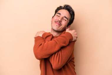 Beyaz tenli genç adam bej arka planda izole edilmiş, gülümsüyor ve mutlu..