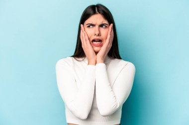 Genç beyaz kadın mavi arka planda izole edilmiş korkmuş ve korkmuş..