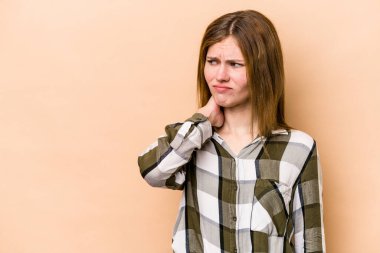 Genç İngiliz kadın bej arka planda izole edilmiş kafasının arkasına dokunuyor, düşünüyor ve bir seçim yapıyor..