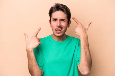 Beyazların arka planında izole edilmiş genç beyaz bir adam işaret parmağıyla hayal kırıklığı jesti yapıyor..