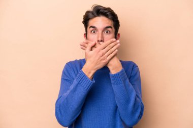 Beyazlı genç bir adam bej arka planda izole edilmiş ağzı kapalı ve elleri endişeli görünüyor..