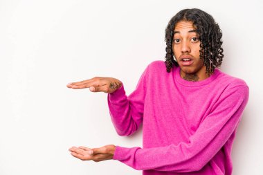 Beyaz arka planda izole edilmiş genç bir Afro-Amerikan erkeği ellerinin arasında bir kopya alanı tutarken şok ve hayrete düştü..