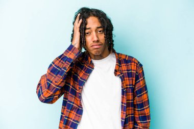 Genç Afrikalı Amerikalı adam mavi arka planda izole edilmiş. Yorgun ve uykulu. Elini başının üstünde tutuyor..
