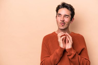 Kafkasyalı genç bir adam, bej arka planda izole edilmiş bir plan kuruyor, bir fikir kuruyor..