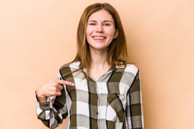 Genç bir İngiliz kadın, bej arka planda izole edilmiş. Gömlek fotokopisini elle gösteriyor. Gururlu ve kendinden emin.