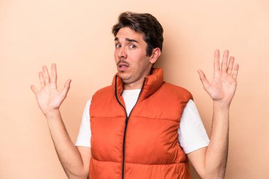 Beyazlı genç bir adam bej arka planda izole edildi. Yakın bir tehlike nedeniyle şoka girdi.