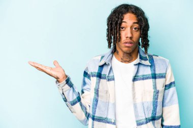 Mavi arka planda izole edilmiş genç Afro-Amerikalı adam, avuç içinin fotokopi alanından etkilenmiş..