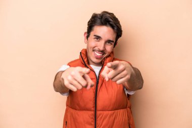 Beyazların arka planında izole edilmiş genç beyaz adam parmaklarıyla ön tarafı işaret ediyor..