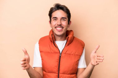 Beyazların arka planında izole edilmiş genç beyaz bir adam iki eliyle bir şey tutuyor, ürün sunumu..