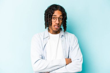 Mavi arka planda izole edilmiş, sıkılmış, yorgun ve dinlenmeye ihtiyacı olan genç Afrikalı Amerikalı bir adam..