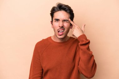 Beyazların arka planında izole edilmiş genç beyaz bir adam işaret parmağıyla hayal kırıklığı jesti yapıyor..