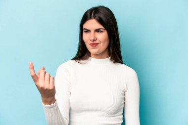 Mavi arka planda izole edilmiş genç beyaz kadın sanki seni davet ediyormuş gibi seni işaret ediyor..