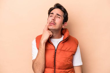 Beyaz tenli genç adam bej arka planda izole edilmiş ağlıyordu, bir şeyden mutsuzdu, ıstırap ve kafa karışıklığı vardı..