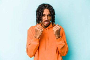 Genç Afrikalı Amerikalı adam mavi arka planda izole edilmiş gergin elleriyle çığlık atıyor..