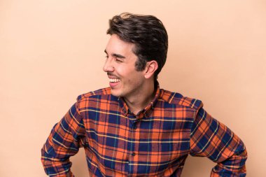 Beyazların arka planında izole edilmiş genç beyaz adam mutlu bir şekilde gülüyor ve ellerini karnının üstünde tutarak eğleniyor..