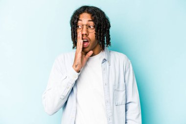 Genç Afrikalı Amerikalı adam mavi arka planda izole edilmiş ve heyecanlı bir şekilde bağırıyor..