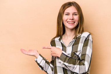 Bej arka planda izole edilmiş genç bir İngiliz kadın, avuç içinde bir fotokopi alanı tutarken heyecanlı..