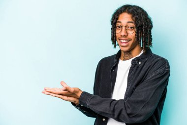Genç Afro-Amerikalı bir adam mavi arka planda izole edilmiş. Elinde bir fotokopi alanı var..