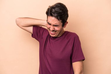 Beyazlı genç bir adam bej arka planda izole edilmiş. Stres yüzünden boynu ağrıyor. Masaj yapıyor ve elle dokunuyor..