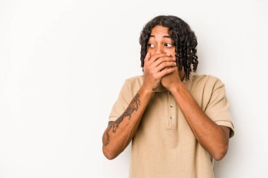 Genç Afrikalı Amerikalı bir adam beyaz arka planda izole edilmiş. Düşünceli bir şekilde bir fotokopi odasına bakıyor. Ağzını eliyle kapatıyor..