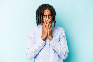 Genç Afro-Amerikalı adam mavi arka planda izole edilmiş ağzı kapalı ve elleri endişeli görünüyor..