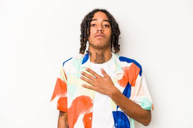 Genç Afrikalı Amerikalı adam beyaz arka planda izole edilmiş bir şekilde yemin ediyor, elini göğsüne koyuyor..