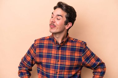 Beyazlı genç bir adam bej arka planda izole edilmiş amaçlarına ve amaçlarına ulaşmayı hayal ediyor.