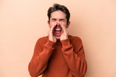 Beyazlı genç adam bej arka planda izole edilmiş ve heyecanlı bir şekilde bağırıyor..