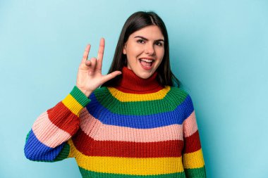 Mavi arka planda izole edilmiş genç beyaz kadın boynuzlarını devrim konsepti olarak gösteriyor..