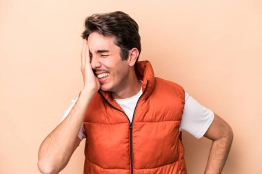 Beyazlı genç bir adam bej arka planda izole edilmiş neşeli bir şekilde gülüyor. Mutluluk kavramı.