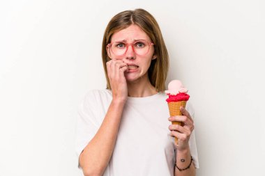 Beyaz arka planda izole edilmiş, tırnak yiyen, gergin ve endişeli bir dondurma tutan genç İngiliz kadın..
