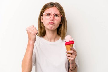 Beyaz arka planda izole edilmiş dondurma tutan genç İngiliz kadın yumruğunu kameraya gösteriyor, agresif yüz ifadesi..