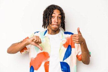 Beyaz arka planda izole edilmiş genç Afro-Amerikalı adam baş parmağını kaldırıyor ve baş parmağını aşağı gösteriyor, zor seçim konsepti