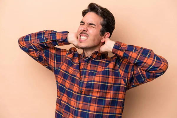 Beyazlı genç bir adam bej arka planda izole edilmiş. Oturaklı yaşam tarzından dolayı boyun ağrısı çekiyor..