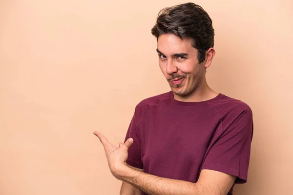 Jovem Caucasiano Isolado Fundo Bege Sorrindo Apontando Para Lado Mostrando — Fotografia de Stock