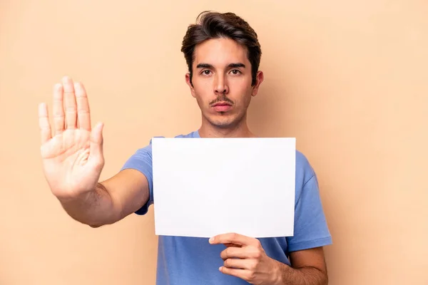 Junger Kaukasischer Mann Mit Einem Plakat Auf Beigem Hintergrund Stehend — Stockfoto