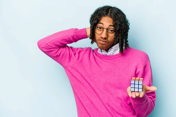 Jovem Afro Americano Segurando Cubo Rubiks Isolado Fundo Azul Tocando — Fotografia de Stock