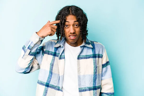 Genç Afro-Amerikalı adam mavi arka planda izole edilmiş işaret parmağıyla hayal kırıklığı jesti gösteriyor..