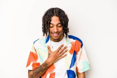 Beyaz arka planda izole edilmiş genç Afrikalı Amerikalı adam elini göğsüne koyduğunda kahkahalar atıyor..