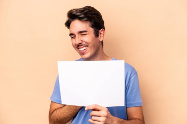 Beyaz bir adam bej arka planda izole edilmiş bir pankart tutuyor. Gülüyor ve eğleniyor..